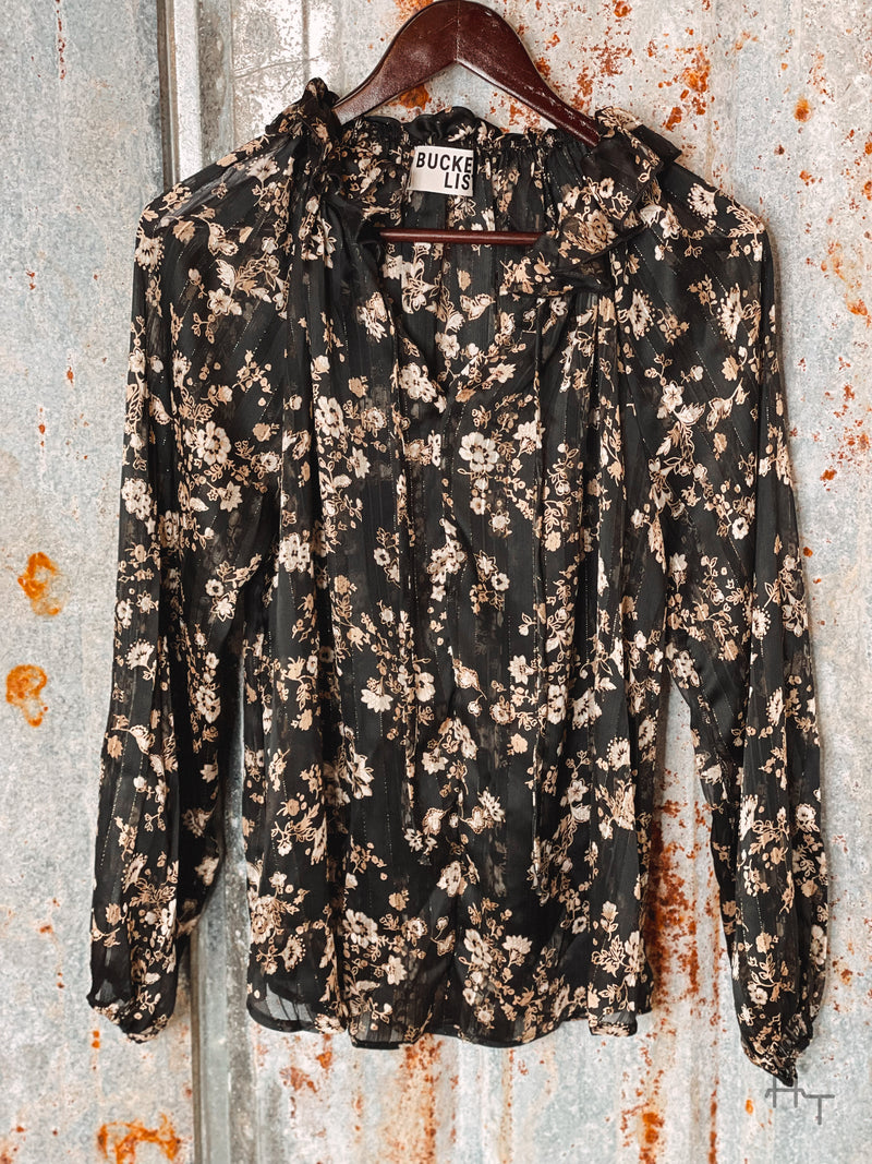 Photo of black and gold floral long sleeve top on a hanger with tin background