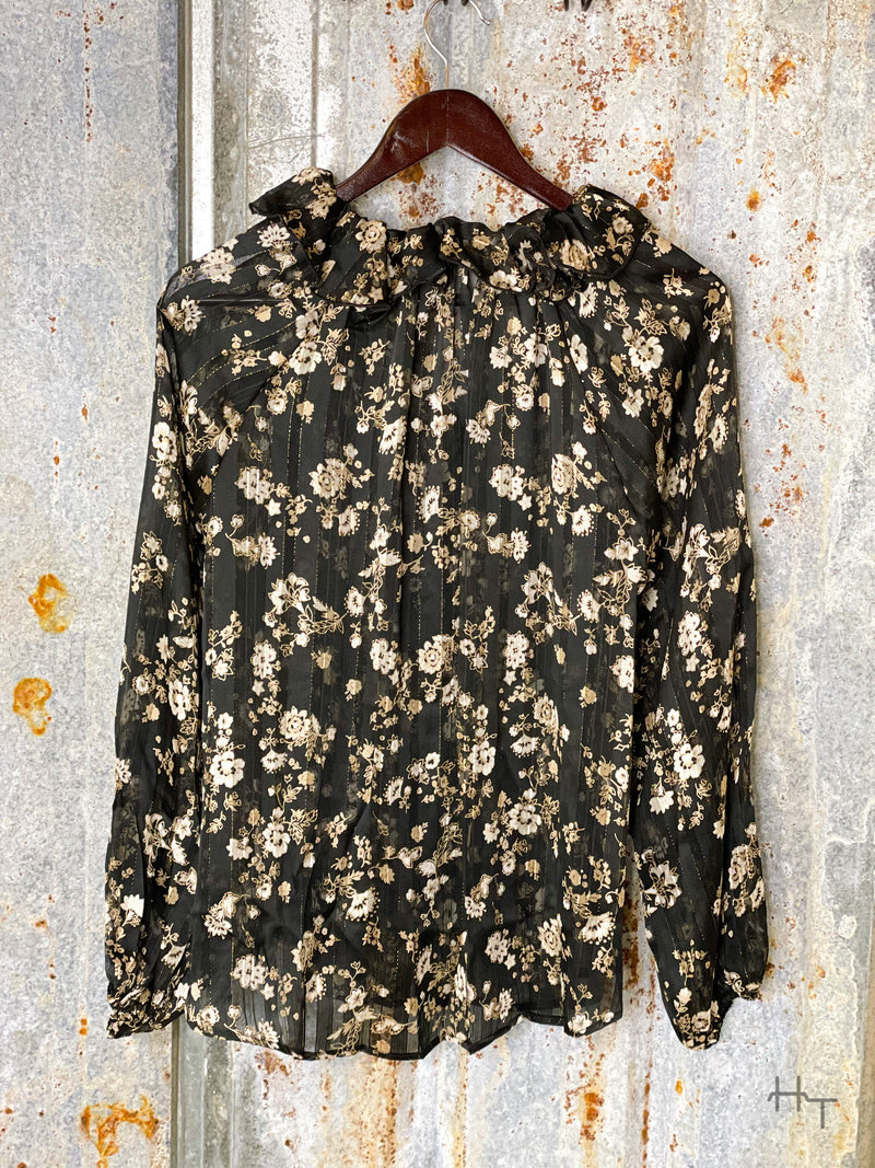 Photo of back of black and gold floral long sleeve top on a hanger with tin background