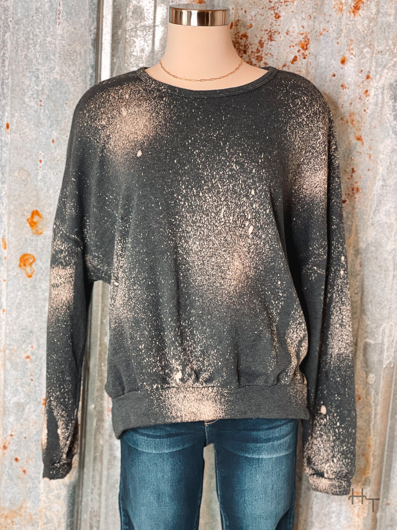 Photo of charcoal sweatshirt with bleach spot details on a mannequin with tin background