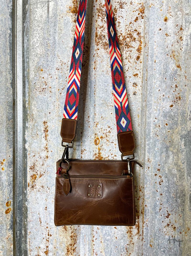 Photo of dark brown leather with STS patch on front with aztec pattern multi color strap with tin background