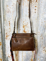 Photo of dark brown leather with STS patch on front 1 matching leather straps and 1 aztec pattern multi color strap with tin background