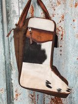 Photo of option B black and white cowhide and brown leather boot bag with front zipper pocket brown canvas sides and leather carrying handles with tin background