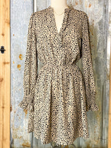 Photo of long sleeve latte brown dress with black spots with a V neck on a mannequin with tin background