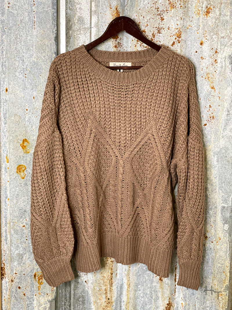 Photo of front view of mocha brown knit sweater on a hanger with tin background