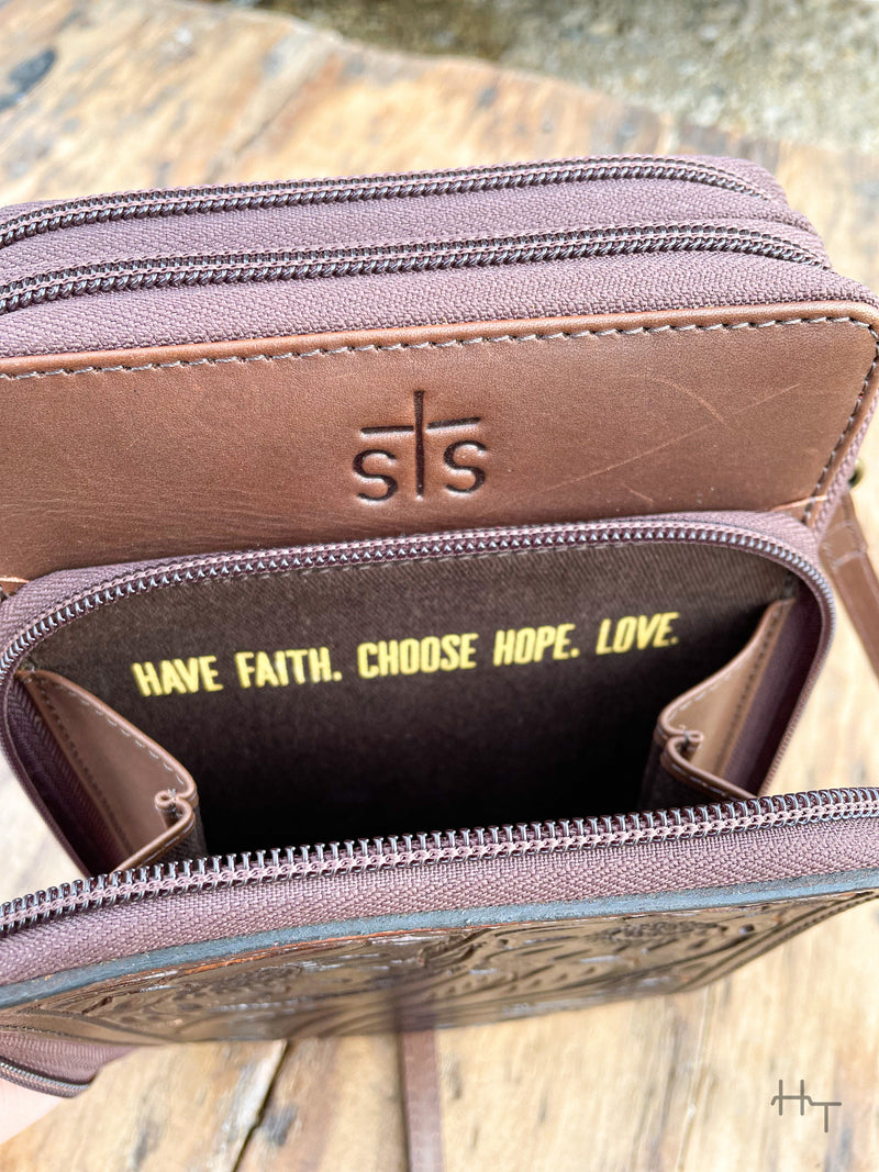 Photo of front zipper pocket of dark brown leather purse with STS stamped on front and the quote Have Faith. Choose Hope. Love. printed on the inside of the pocket.