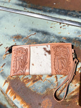 Image of backside of B option of yipee kiyay clutch wallet with veggie tan leather that is stamped with a floral design on each side with white cowhide with brown speckles in the middle.