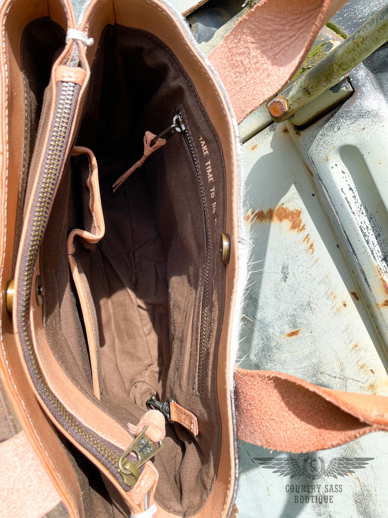 Image of 1 interior compartment of the Yipee Kiyay tote purse.  Brown cloth liner with 2 slip pockets, 1 zipper pocket, key snap, and an inspirational quote " Take time to do what makes your soul happy".